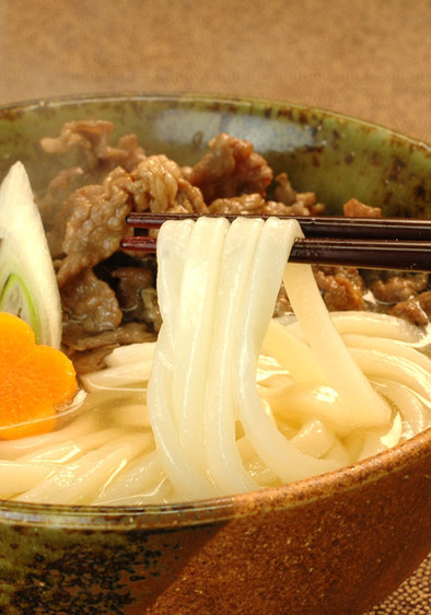 めんつゆで牛肉を煮込む肉うどんの写真